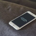 A smartphone with a humorous lock screen message placed on a grey couch, emphasizing privacy.