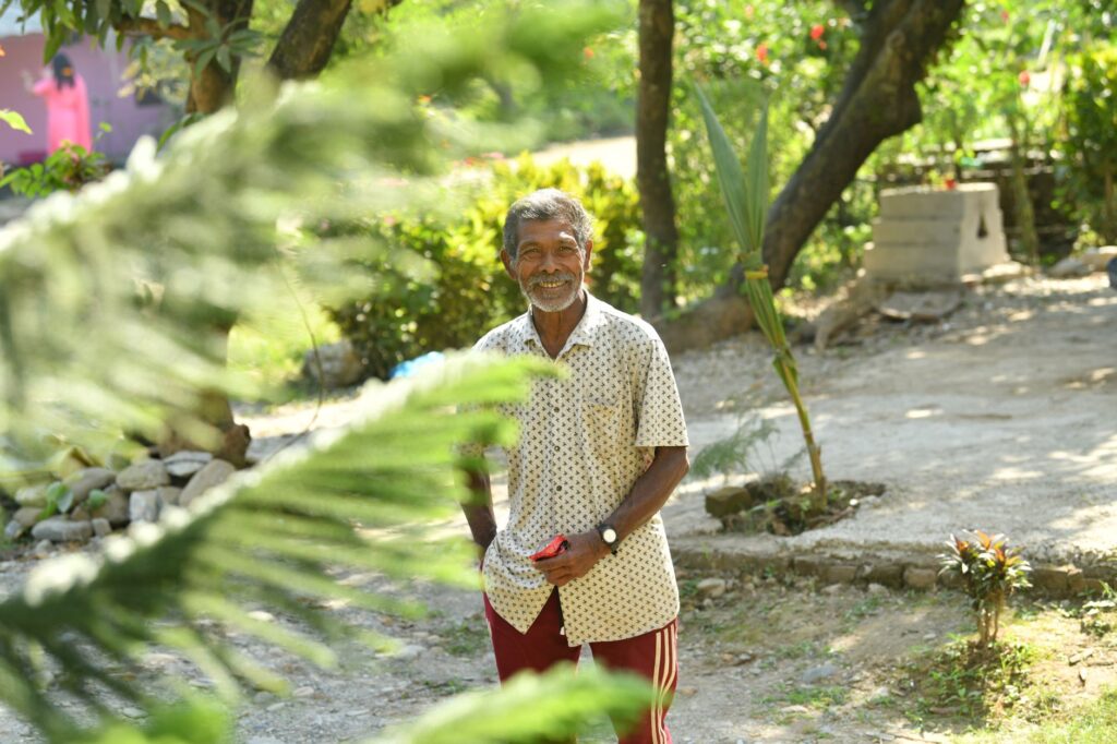 Happy senior man enjoying a bright sunny day in a lush garden landscape.