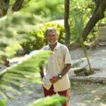 Happy senior man enjoying a bright sunny day in a lush garden landscape.