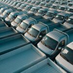 Aerial perspective showcasing a vast array of new silver pickup trucks parked in an orderly fashion.