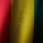 Close-up of the vibrant Guinea flag showing red, yellow, and green textile textures.