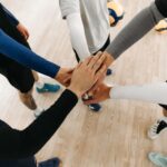 Close-up of athletes joining hands in a motivational sports huddle on an indoor court.
