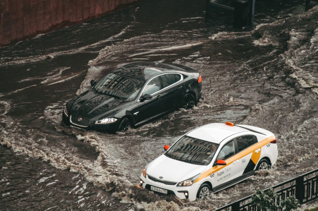 Cars navigating through a flooded city street, showcasing urban chaos and weather impacts.