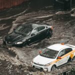 Cars navigating through a flooded city street, showcasing urban chaos and weather impacts.