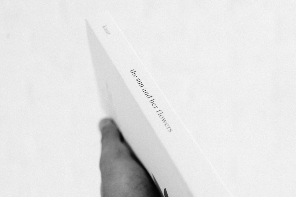 Black and white photo of a hand holding a book, emphasizing simplicity and elegance.