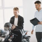 Two men at a motorcycle dealership discussing a motorbike purchase.