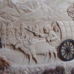 A detailed bas-relief depicting oxen pulling a wagon through a mountainous landscape, showcasing historical travel.