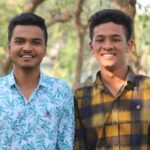 Two young men smiling outdoors in a sunny park, enjoying a summer day.