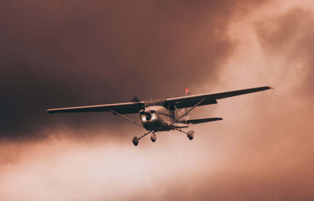 Airplane flying through dark and dramatic storm clouds, showcasing intense weather conditions.