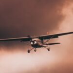 Airplane flying through dark and dramatic storm clouds, showcasing intense weather conditions.