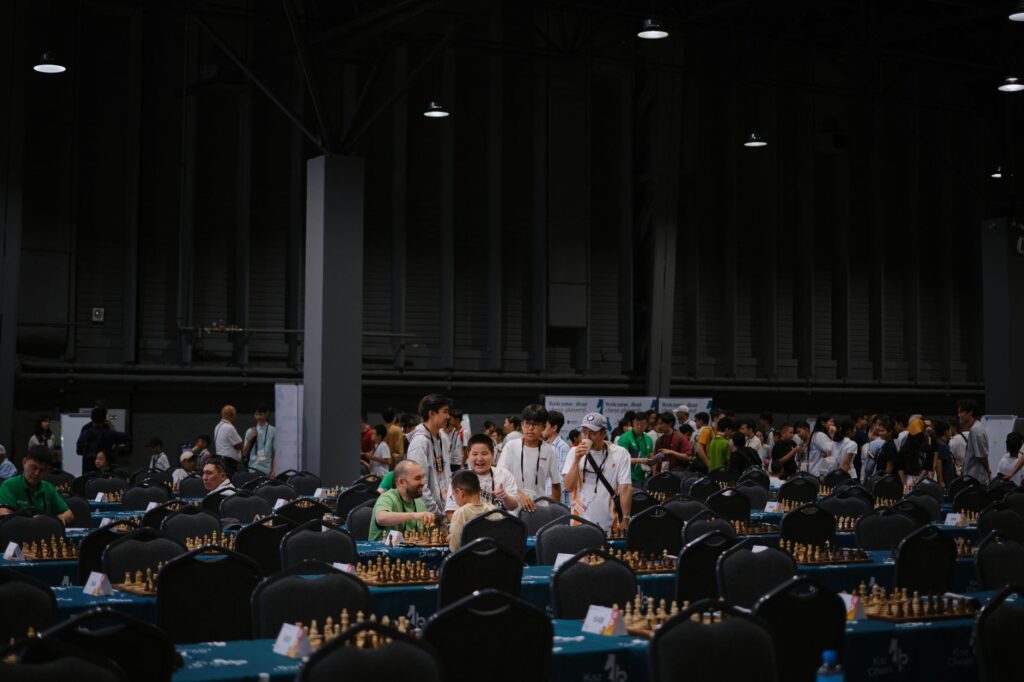 Indoor chess tournament with diverse participants gathering around tables.