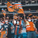 Fans enthusiastically wave FC Barcelona flags at a football match, showcasing team spirit and unity.