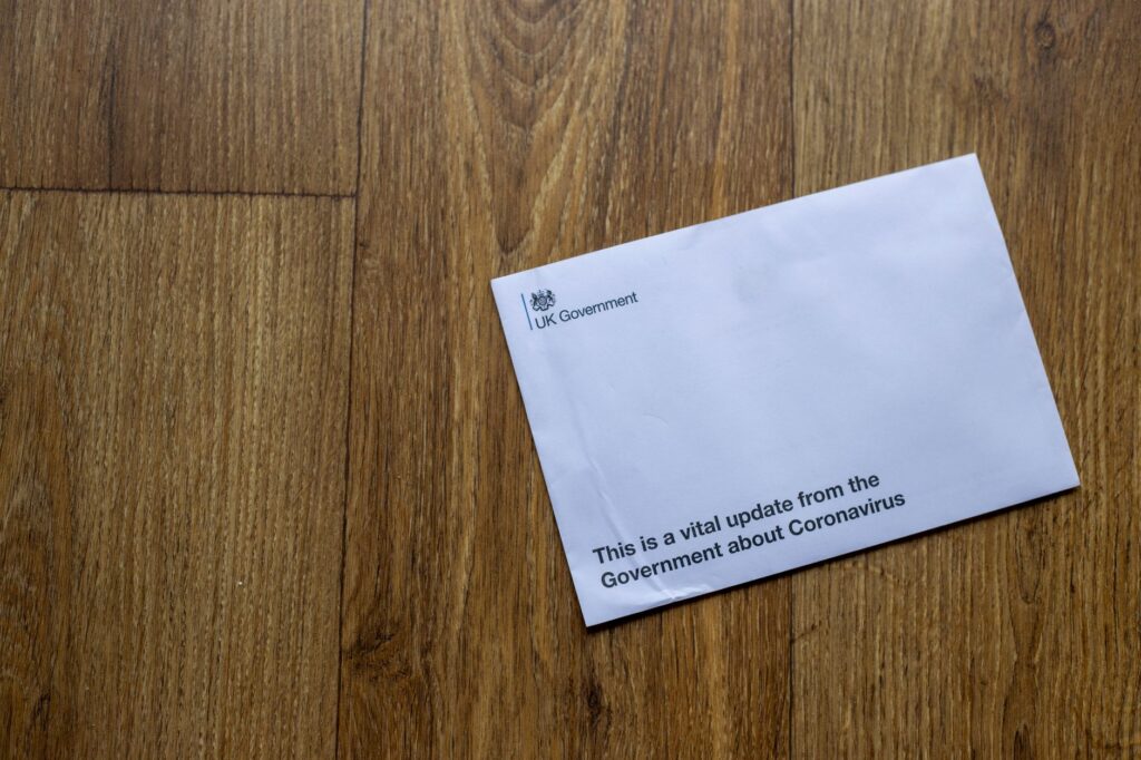 A UK Government envelope with coronavirus update on a wooden floor.