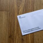 A UK Government envelope with coronavirus update on a wooden floor.