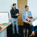 Colleagues joyfully applaud a new hire announcement in a modern office setting.