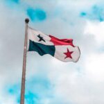 The flag of Panama waving on a flagpole with vibrant blue sky and clouds in the background.