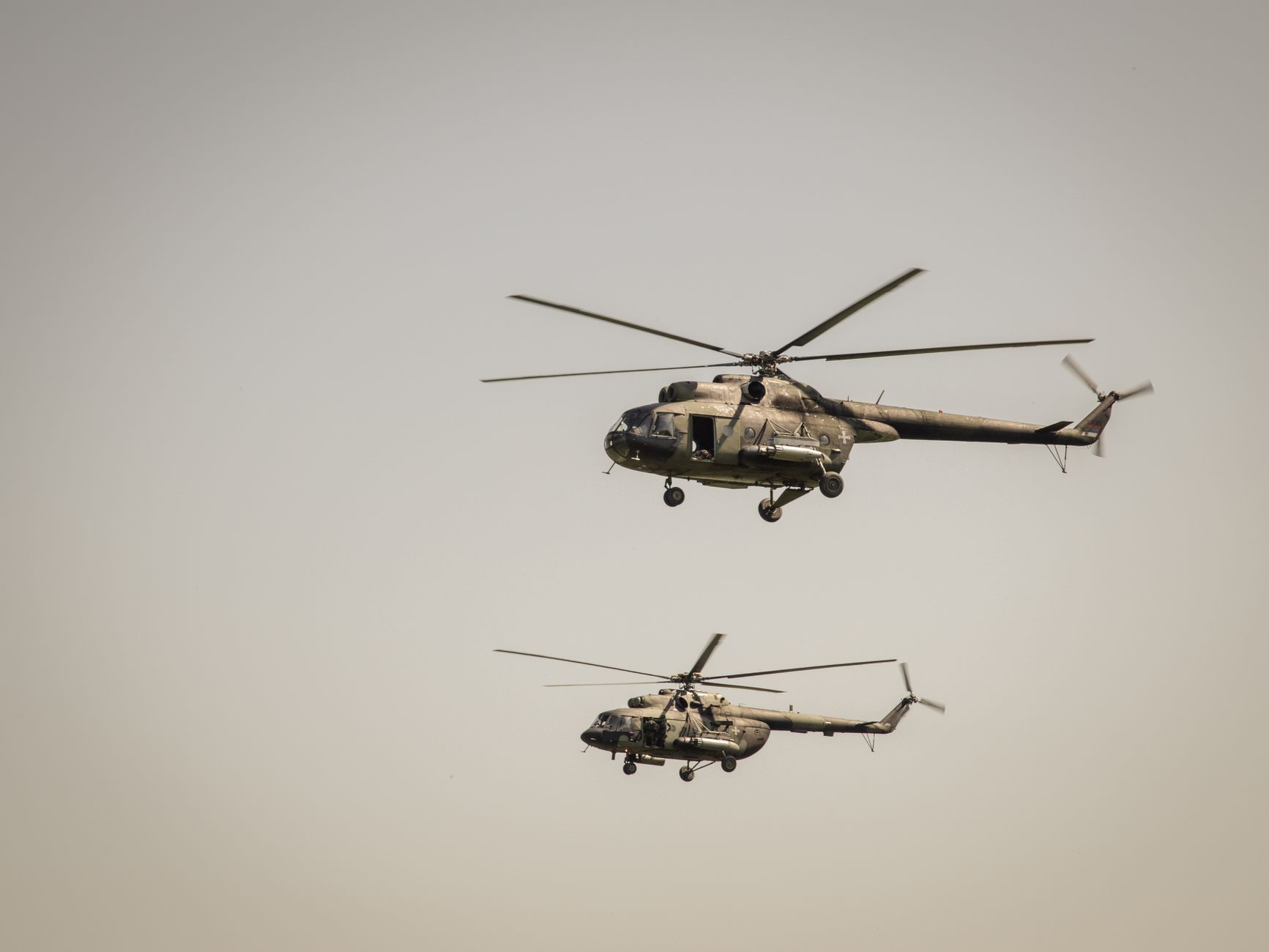 Two military helicopters flying at low altitude in clear sky over Beograd, Serbia.
