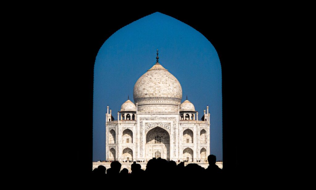 Taj Mahal framed through an archway with blue sky in Agra, India.