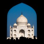 Taj Mahal framed through an archway with blue sky in Agra, India.