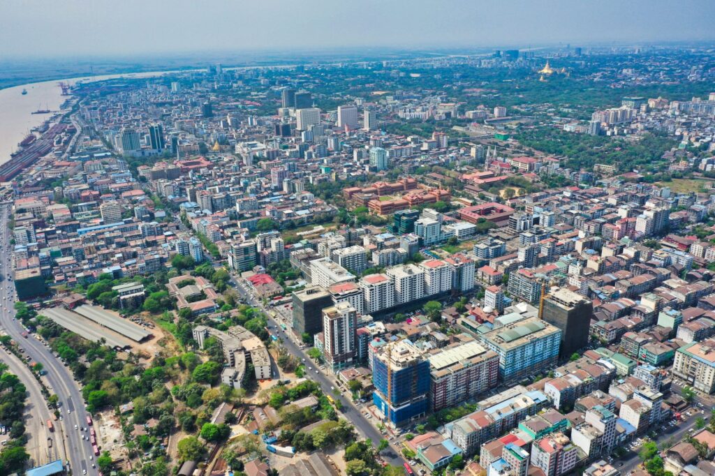 Vibrant aerial view of Yangon showcasing the urban skyline, lush greenery, and golden pagodas.