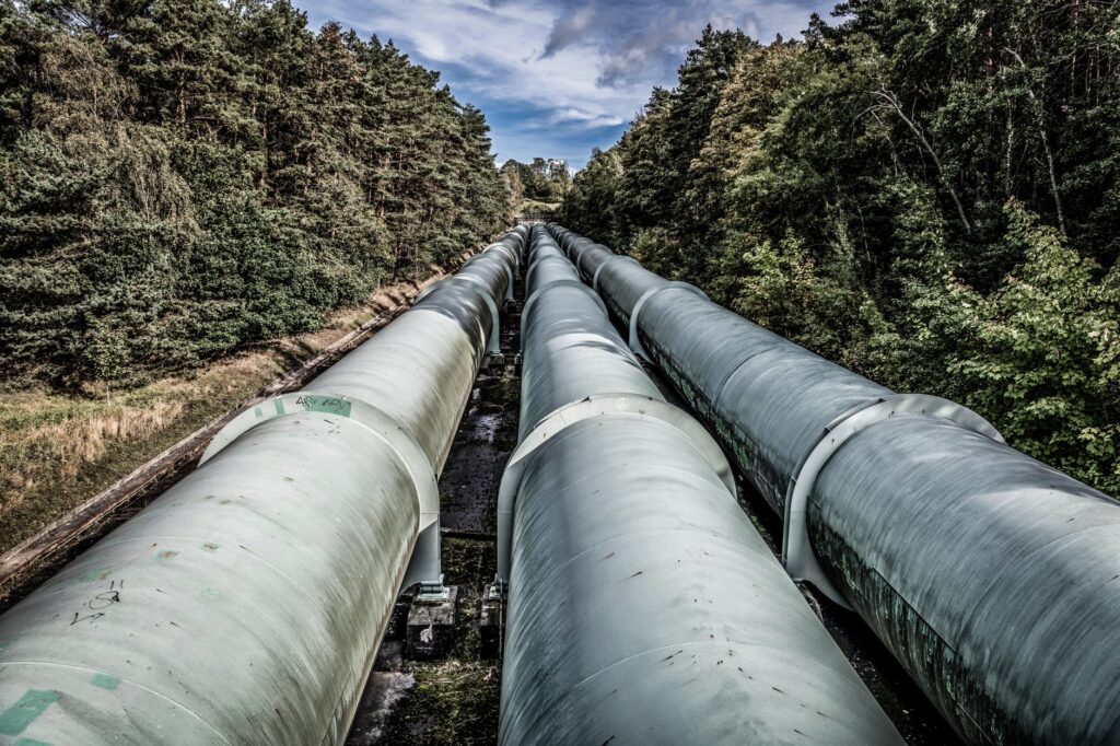 View of large industrial pipelines running through a lush forest landscape.