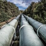 View of large industrial pipelines running through a lush forest landscape.