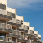 A modern apartment building with distinct balconies against a clear blue sky.
