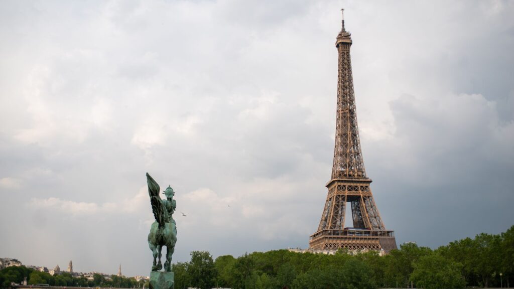 Iconic view of the Eiffel Tower alongside the equestrian statue La France Renaissante in Paris.