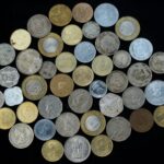 A variety of international coins displayed on a black background, showcasing different currencies and designs.