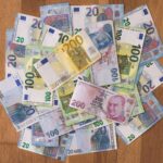A pile of Euro and Turkish Lira banknotes scattered on a wooden surface, showcasing various denominations.