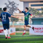 Two soccer players celebrate a goal on a field during a sports event in Hanoi, Vietnam.