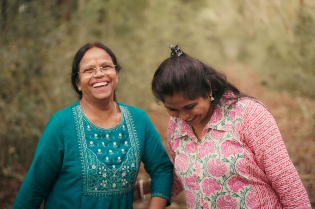 Joyful moment of a mother and daughter laughing together in a natural outdoor setting.