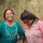 Joyful moment of a mother and daughter laughing together in a natural outdoor setting.