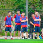 Soccer team members training outdoors in Hanoi, Vietnam, wearing colorful sportswear.
