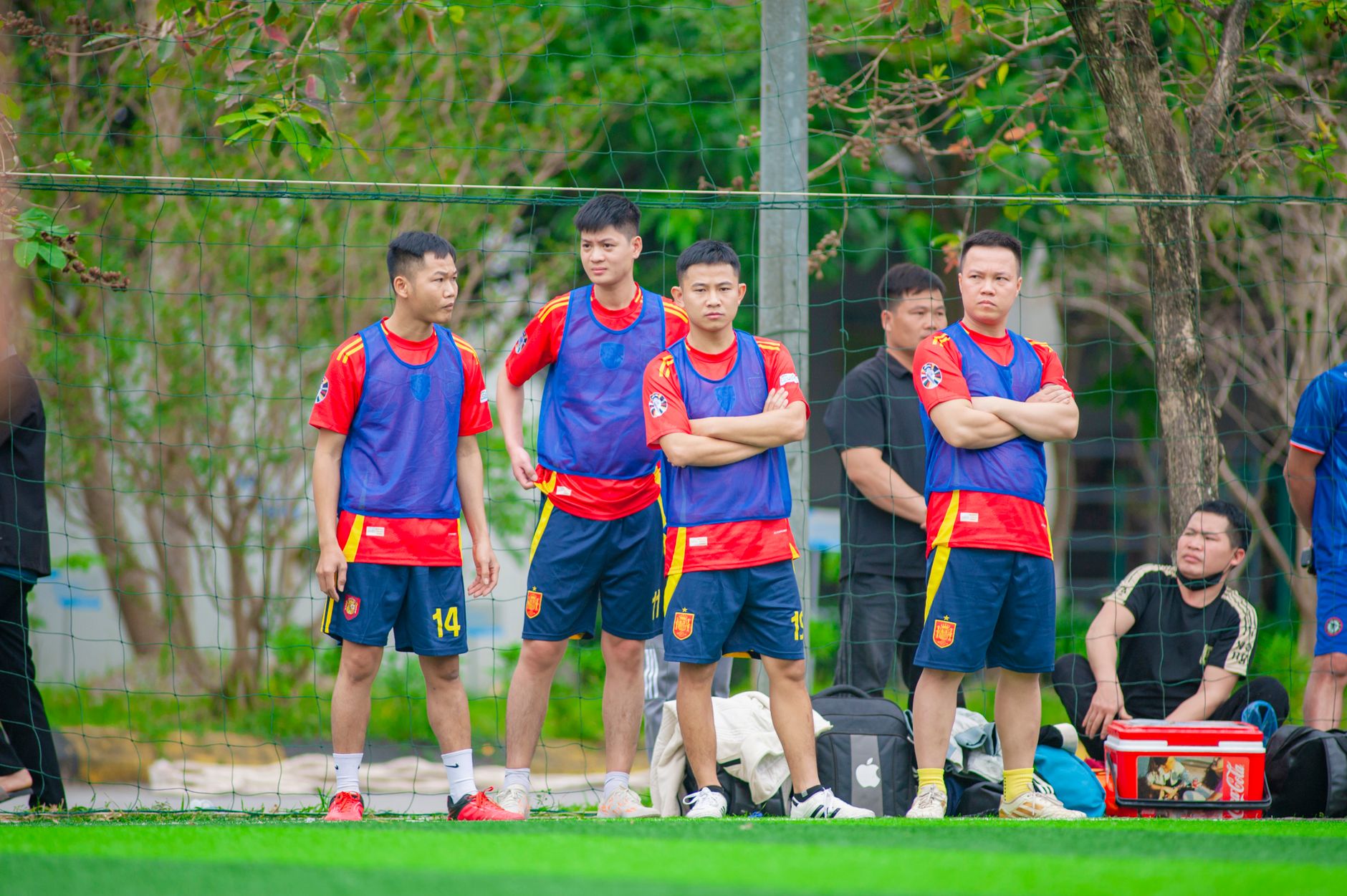 Soccer team members training outdoors in Hanoi, Vietnam, wearing colorful sportswear.