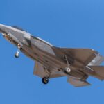 F35 fighter jet in flight with landing gear visible against clear blue sky, showcasing military aviation prowess.