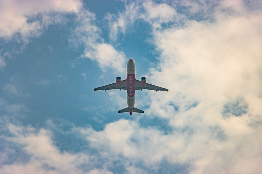 An Air India airplane flies overhead against a backdrop of blue skies and fluffy clouds in New Delhi.