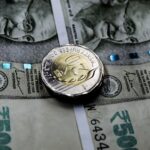 Close-up image of Indian rupee notes with a twenty rupee coin, illustrating financial themes.