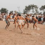 Men engage in a traditional Kabaddi match in Sillanwali, Pakistan with a large crowd watching.