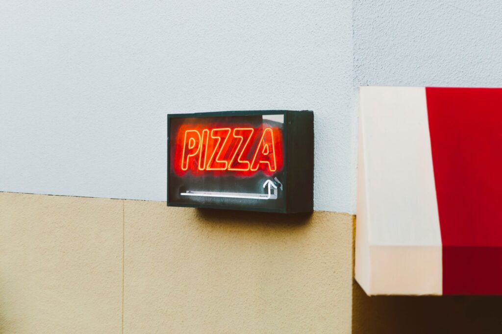 Bright neon pizza sign on the exterior of a San Francisco building, capturing vibrant urban life.