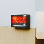 Bright neon pizza sign on the exterior of a San Francisco building, capturing vibrant urban life.