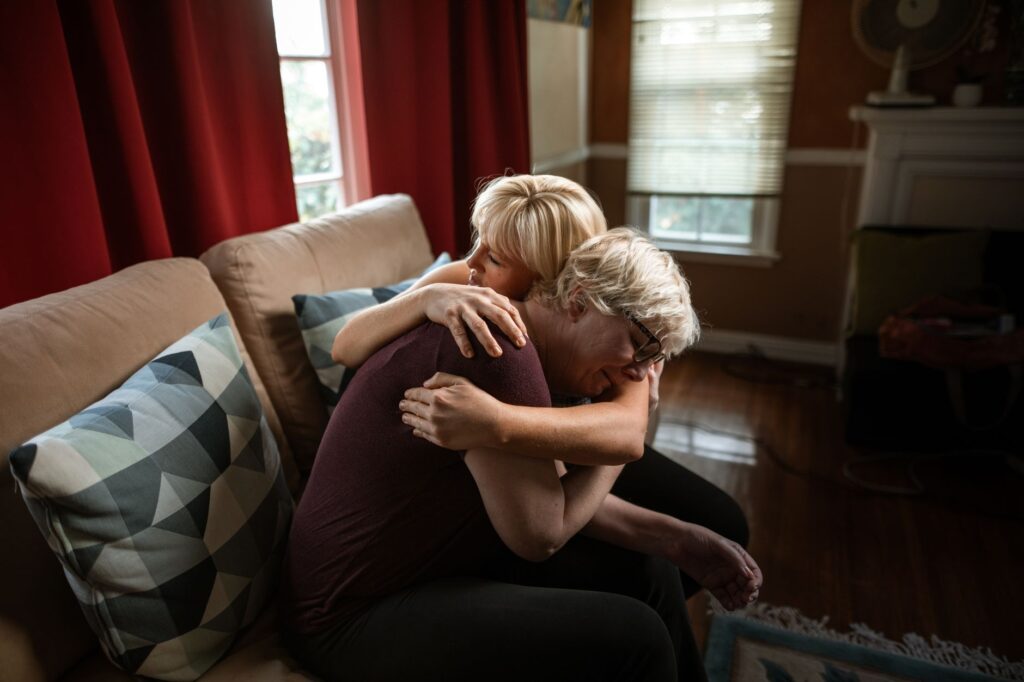 An emotional and supportive embrace between a couple on a sofa, showcasing affection and togetherness in a cozy home setting.
