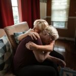 An emotional and supportive embrace between a couple on a sofa, showcasing affection and togetherness in a cozy home setting.
