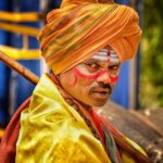 Traditional Indian man with painted face and turban, vibrant cultural expression.