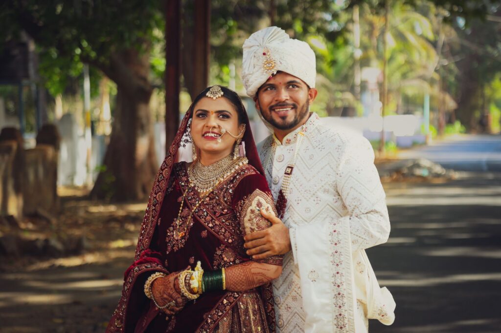 A joyful couple in traditional wedding attire captured outdoors on their special day.