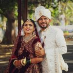 A joyful couple in traditional wedding attire captured outdoors on their special day.