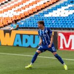 Soccer player in blue uniform celebrates goal on a sunny field