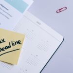 A sticky note highlights tax deadline on a calendar alongside documents, emphasizing financial planning.