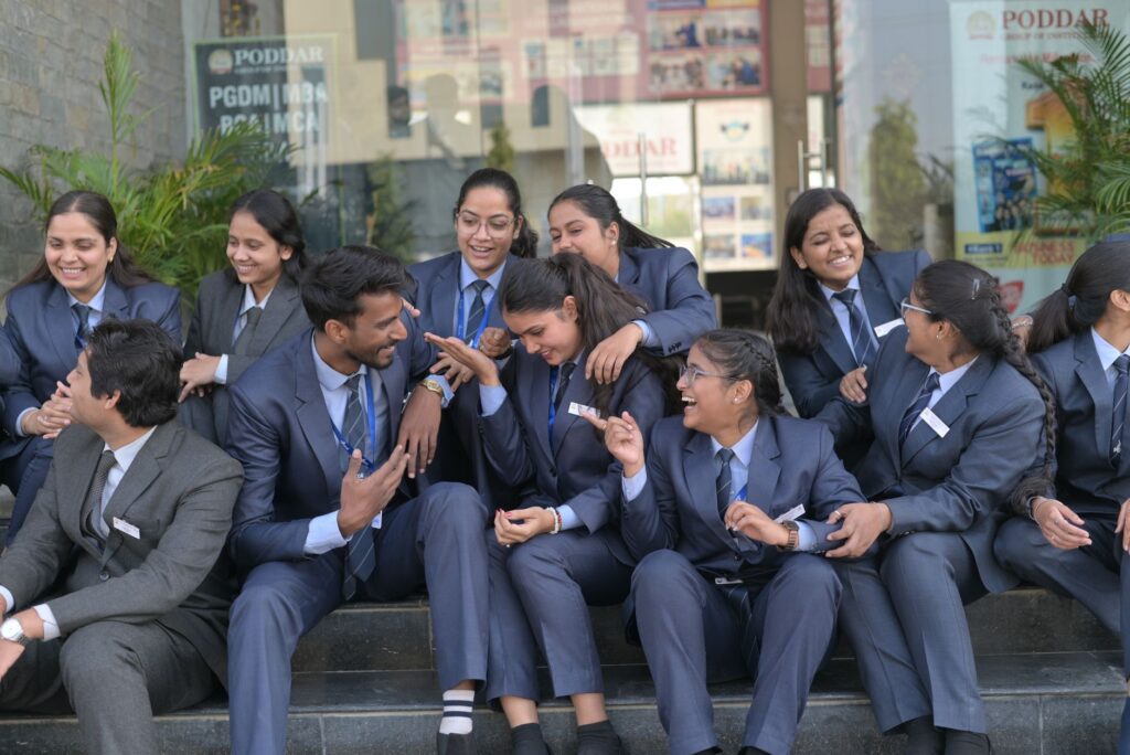 Business students in formal attire enjoying a lively conversation outdoors, showcasing teamwork and camaraderie.