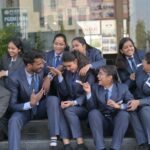 Business students in formal attire enjoying a lively conversation outdoors, showcasing teamwork and camaraderie.